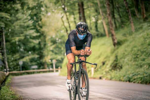 Чоловік бере участь у тріатлоні з велосипедом у гірській місцевості з маскою проти ковадлового вірусу
 - Фото, зображення