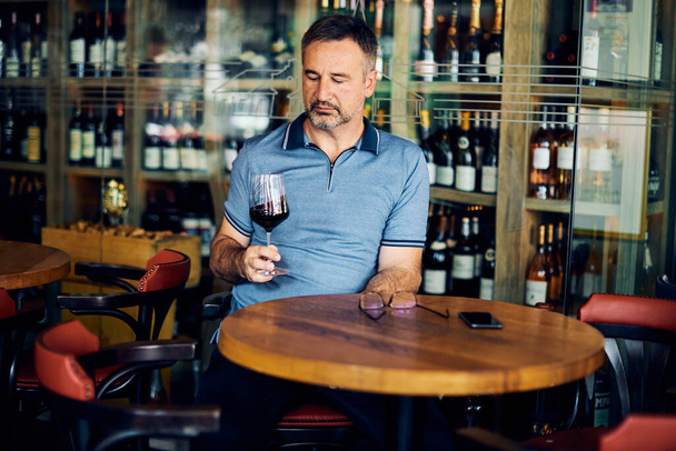 Starší dospělý ochutnávka vína sedí ve vinařství a ochutnávka vína. - Fotografie, Obrázek