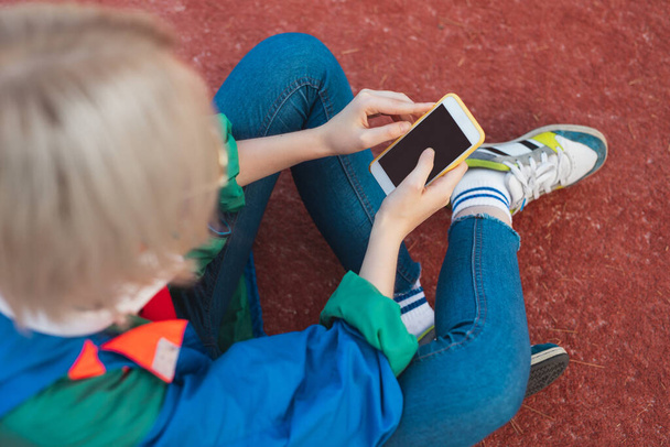 Unrecognizable teenager using smartphone on playground - Фото, изображение