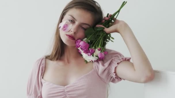 attrayant belle jeune femme modèle avec des fleurs regardant et posant à la caméra - Séquence, vidéo