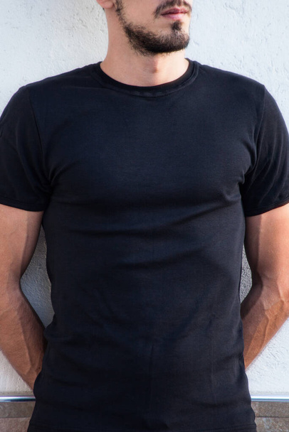 jeune homme en t-shirt noir extérieur tourné devant blanc t-shirt mock up gros plan - Photo, image