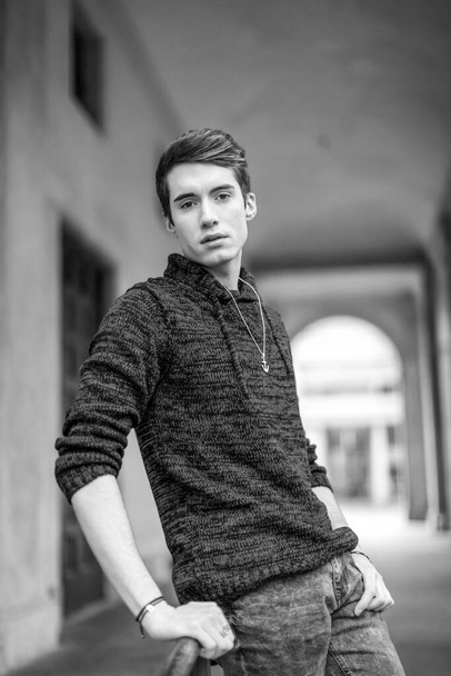beautiful guy poses in the city center with jacket and dark shirt. High quality photo - Photo, image