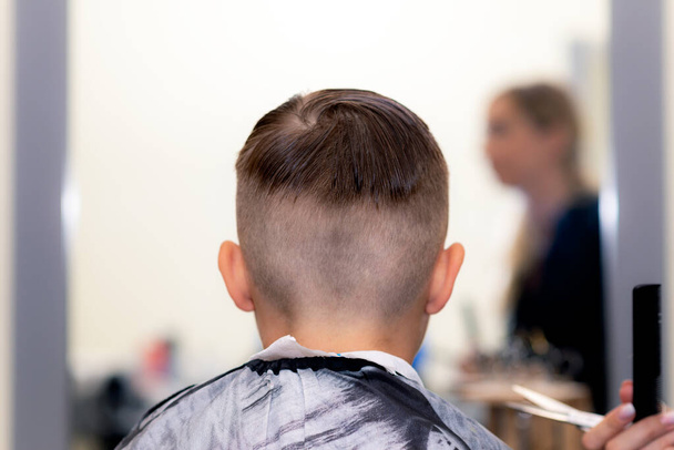 Close up vista traseira caucasiano americano bonito menino da escola corte de cabelo na moda brilhante barbearia moderna. - Foto, Imagem