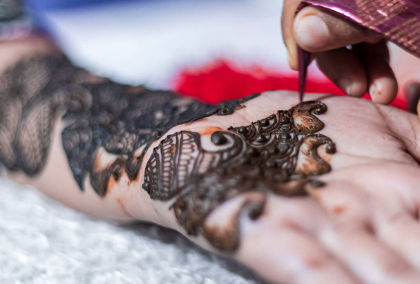 Closeup of Woman designing Henna or Mehendi Tatto on the palm of a girl - Foto, Imagen