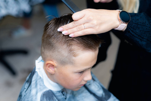 Side view Close up of kaukaski amerykański ładna szkoła chłopiec miał modną fryzurę z strzyżenia włosów w jasny nowoczesny fryzjer. - Zdjęcie, obraz