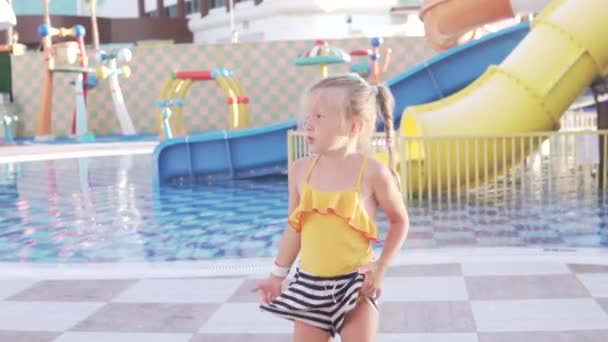 Een klein meisje in een badpak wandelt in een verlaten waterpark in de zomer - Video