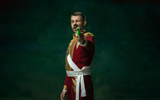 Young man as Nicholas II on dark green background. Retro style, comparison of eras concept. - Photo, Image