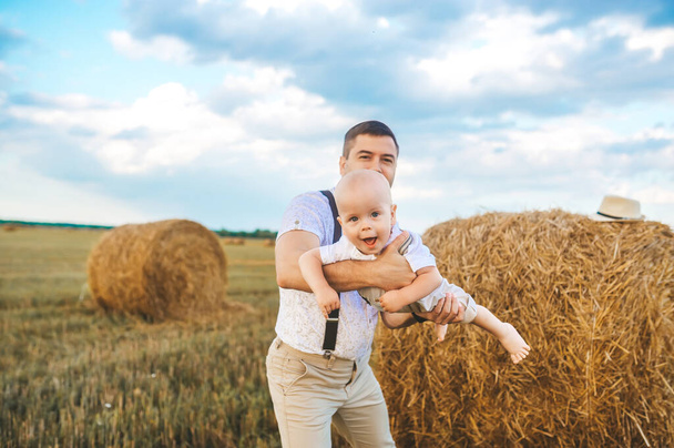 Dad, mom playing with his baby son in wheat field on sunset. The concept of summer holiday. Father's, baby's day. Family spending time together on nature. Family look. - Foto, immagini
