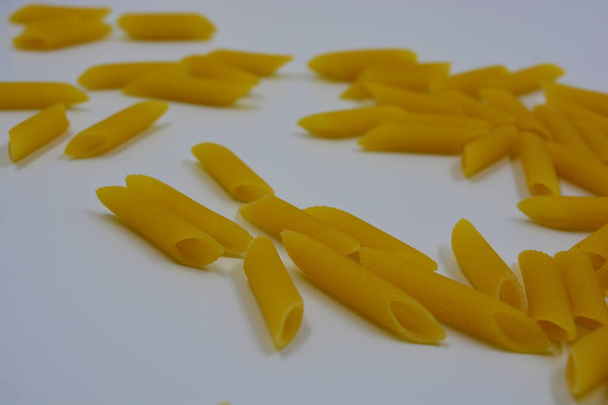 Pâtes jaunes italiennes, pâtes aux nouilles, plumes de blé dur éparpillées sur fond blanc. - Photo, image