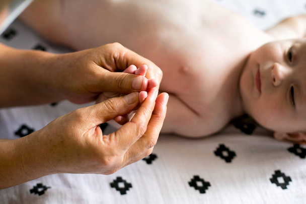 Madre hace masaje bebé recién nacido, aplicar aceite en la mano, con fondo blanco. - Foto, Imagen