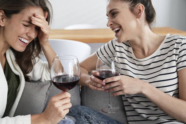 Δύο φίλοι γελάνε μ 'ένα ποτήρι κρασί στο χέρι.                                - Φωτογραφία, εικόνα