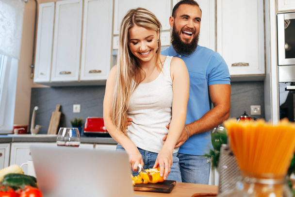Young loving couple cooking together in kitchen - Valokuva, kuva
