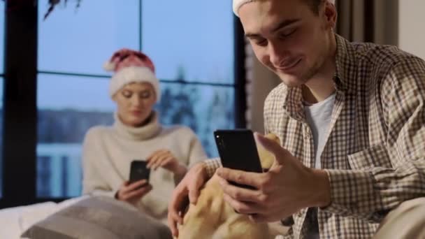 New Year. Young Couple In Santa Hats On New Years Eve At Home With Their Dog. - Materiał filmowy, wideo