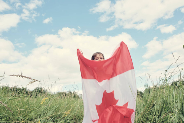 Menino feliz acenando com a bandeira do Canadá enquanto corre - Foto, Imagem