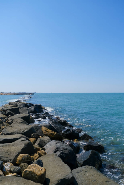 rocas con salpicaduras de olas marinas y cielo azul roma ostia. Foto de alta calidad - Foto, imagen