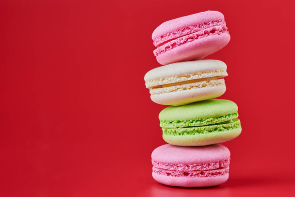 Macaroons on red background. Colorful small cookie from ground almonds and coconut. Popular confectionery. Tasty snack food for take away, copy space - Photo, Image