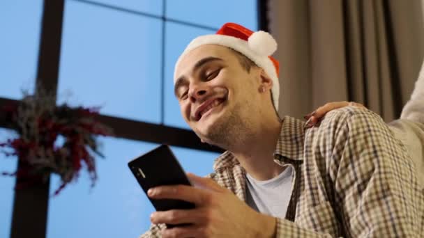 New Year. Young Couple In Santa Hats With Mobile Phones In Hands. - Filmagem, Vídeo