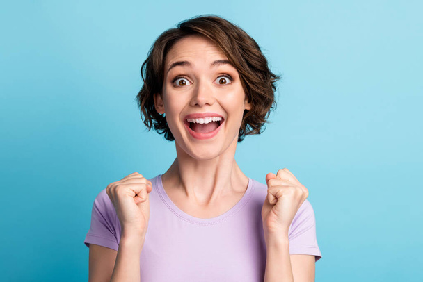 Portrait of astonished delighted girl impressed incredible lottery lucky win raise fists scream wow omg wear lilac outfit isolated over blue color background - Foto, Imagem