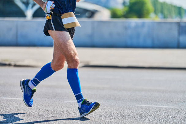 Juokseva mies. Urheilija lenkkeilee urheiluvaatteissa kaupungin tiellä. Terveellinen elämäntapa, kuntoiluharrastus. Street harjoitus, sprinting ulkona - Valokuva, kuva