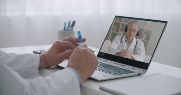 online conferentie van gezondheidswerkers, oudere professor in de geneeskunde geeft lezingen op het scherm van laptop van arts in het ziekenhuis - Video