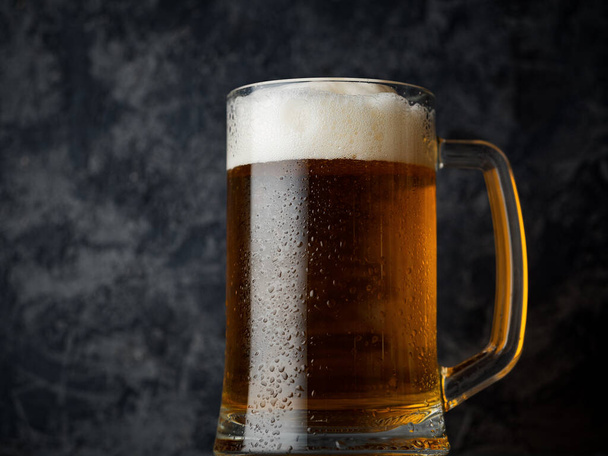 Ein Becher helles Bier auf dunklem Betongrund - Foto, Bild