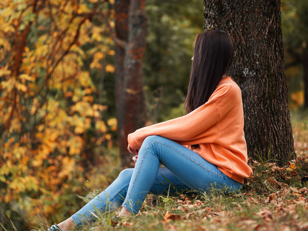 Autumn mood. Beautiful girl in orange hoodie in autumn Park - Foto, imagen