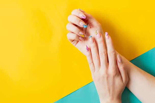 youth summer funny cheerful colorful acrylic manicure. Gel polish nails with a fun stylish art design. Colored background yellow. Place for text copy space. beauty salon trendy  - Φωτογραφία, εικόνα