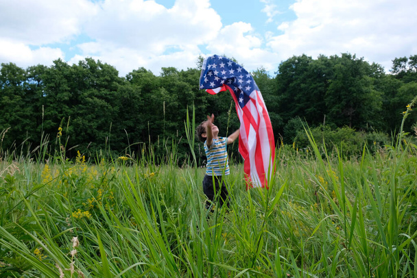 愛国的な休日。アメリカの旗を持つ若い男の子。米国は7月4日を祝う. - 写真・画像