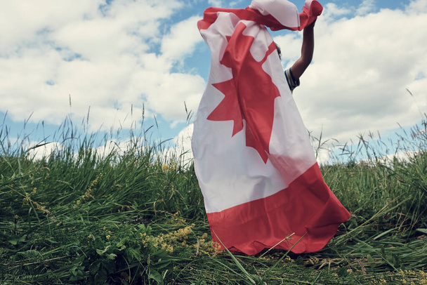 Niño feliz ondeando la bandera de Canadá mientras corre - Foto, Imagen