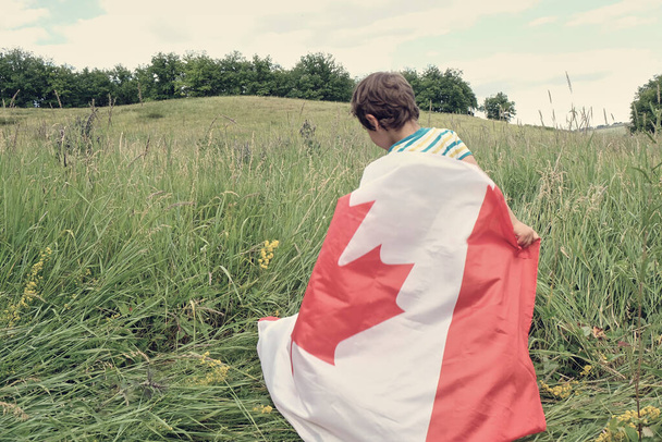 Menino feliz acenando com a bandeira do Canadá enquanto corre - Foto, Imagem