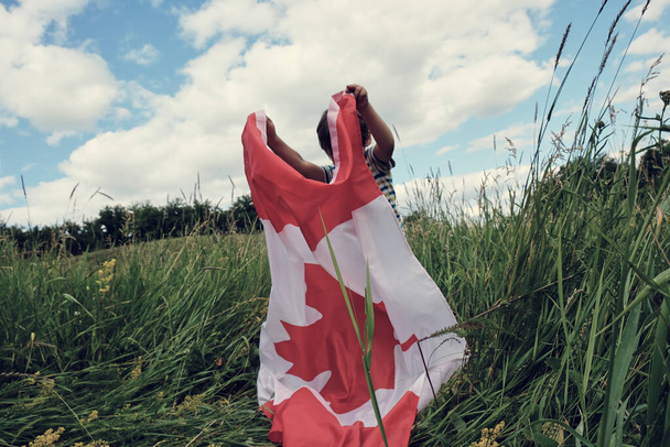 Bambino felice sventola la bandiera del Canada mentre corre - Foto, immagini