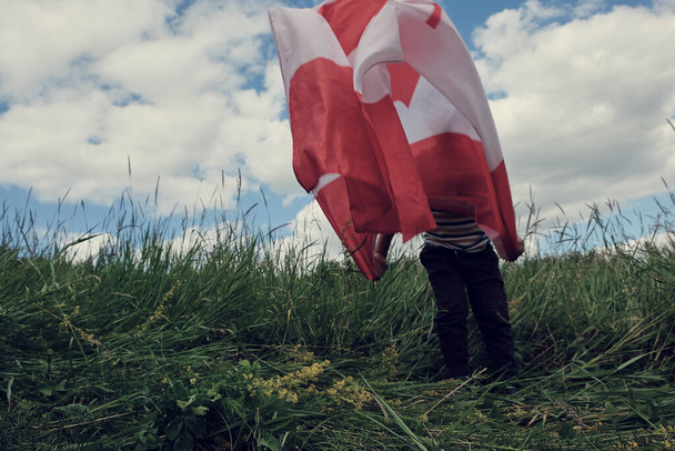 Niño feliz ondeando la bandera de Canadá mientras corre - Foto, imagen