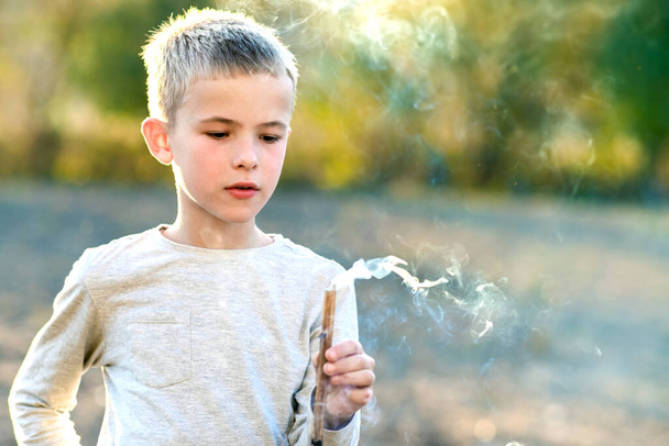 Kind jongen spelen met roken houten stok buiten. - Foto, afbeelding
