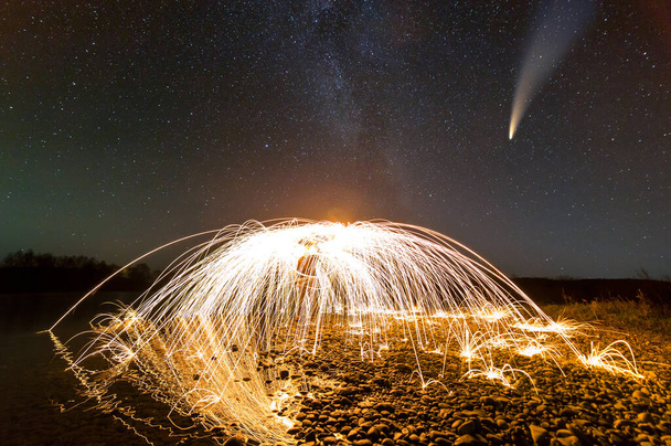 Lange Belichtung der spinnenden Stahlwolle in abstrakten Kreis machen Feuerwerk Schauer von gelb glühenden Funken mit dunklem Sternenhimmel über. - Foto, Bild