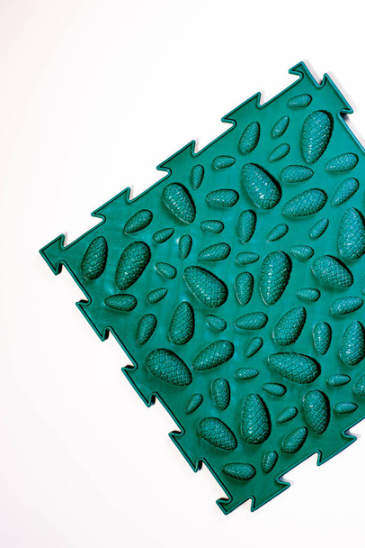 Een groene orthopedische mat met het ontwerp van kegels om platte voeten te voorkomen. - Foto, afbeelding