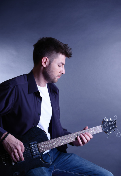 Young musician playing guitar on gray background - 写真・画像