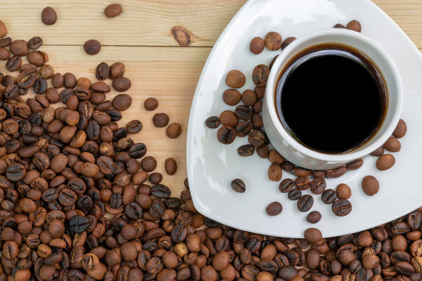 Espresso musta kahvi valkoinen kuppi paahdettuja kahvipapuja puupinnalla. - Valokuva, kuva