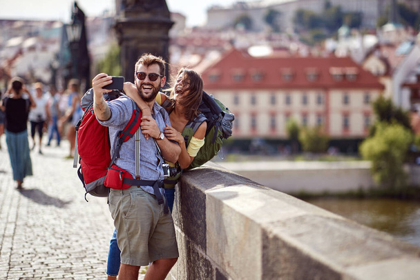Smiling travelers couple in love walking on a street of Prague city and make selfie.  - Foto, imagen