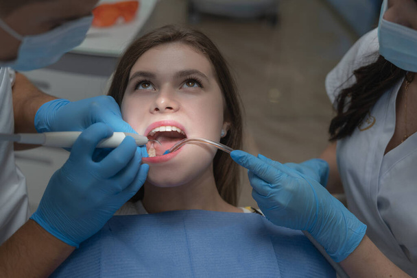 Atraktivní mladá žena na zubní klinice s mužským zubařem. Zdravé zuby koncept. - Fotografie, Obrázek