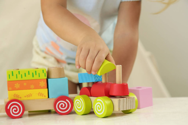 Batole dívka hrající si s dřevěným vláčkem z dřevěných bloků - vzdělávací hračky pro předškolní a mateřské dítě.  - Fotografie, Obrázek