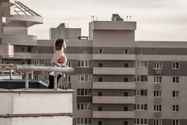 Beautiful girl on the roof of a high-rise skyscraper - Фото, зображення