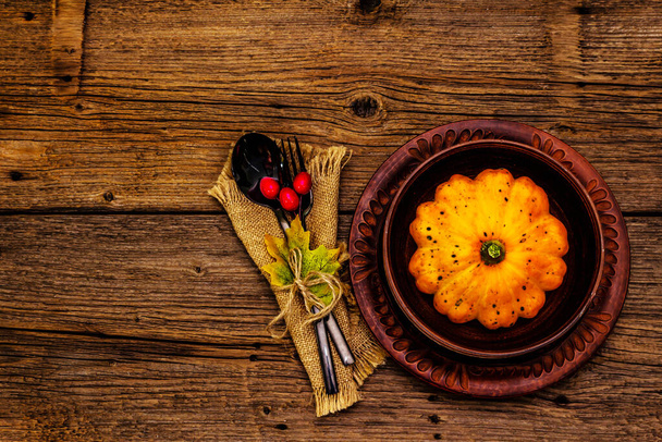 Φθινόπωρο και Ημέρα των Ευχαριστιών σερβίτσιο. Συγκομιδή κολοκύθας και μούρων, πολύχρωμα φύλλα, κεραμικά πιάτα, πιρούνι και κουτάλι, vintage πετσέτα. Πτώση μαχαιροπήρουνα ξύλινο φόντο, κορυφαία άποψη - Φωτογραφία, εικόνα