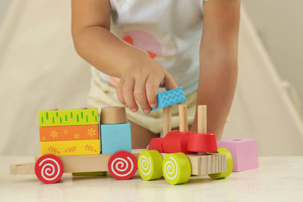 Batole dívka hrající si s dřevěným vláčkem z dřevěných bloků - vzdělávací hračky pro předškolní a mateřské dítě. - Fotografie, Obrázek