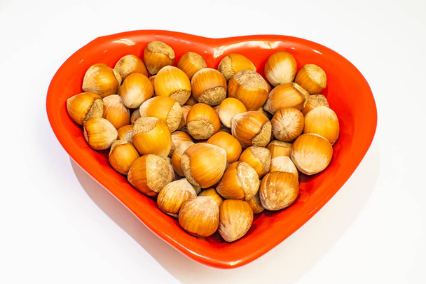 shelled hazelnuts on a red plate with heart figures - Zdjęcie, obraz