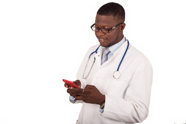 Sağlık hizmetleri, insanlar, teknoloji ve tıp kavramı. Steteskop ve gözlüklü beyaz önlüklü doktor beyaz arka planda cep telefonu kullanıyor. - Fotoğraf, Görsel