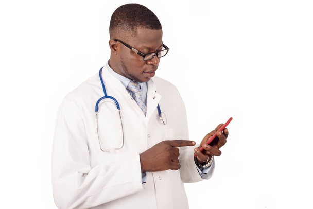 concept of health care, people, technology and medicine - doctor man in white coat with stethoscope and glasses using a cellphone on white background - Photo, Image