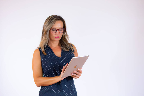 Woman in blue shirt thoughtful with tablet - Photo, Image