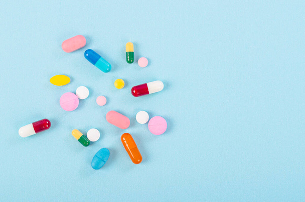 Medical pills and tablets spilling on blue background. - Foto, Imagen