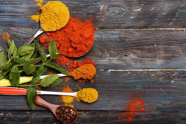 Colorful spices and wooden spoon on black background - Zdjęcie, obraz