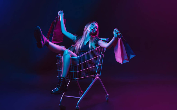 Portrait of young woman in neon light on dark backgound. The human emotions, black friday, cyber monday, purchases, sales, finance concept. - Φωτογραφία, εικόνα